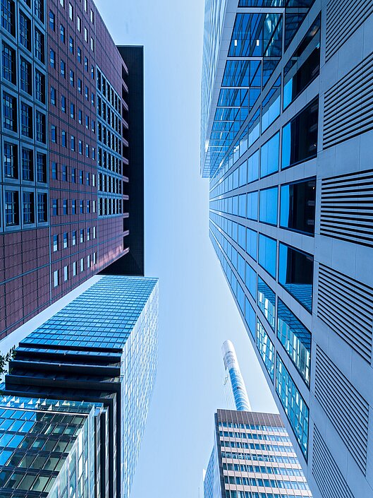 Vier Hochhäuser aus Frankfurt aus der Perspektive, dass der Betrachter auf der Straße steht und nach oben in den Himmel schaut